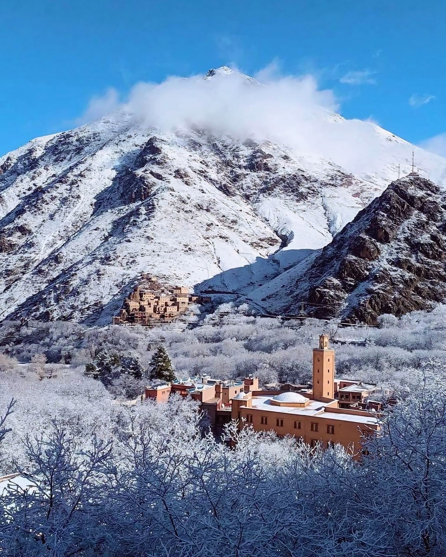 Imlil village in winter — snow-covered Atlas Mountains with Toubkal peak and the mosque